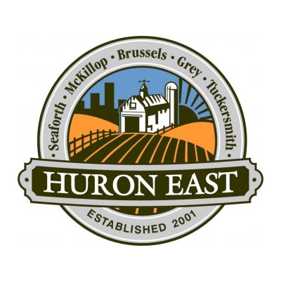 Round logo that says Huron East, with a barn, fields, smoke stacks